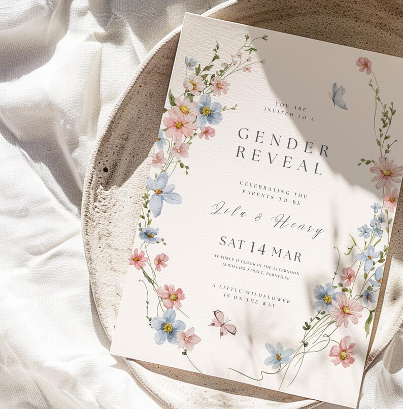 May include: A rectangular gender reveal invitation card featuring watercolor illustrations of pink and blue wildflowers and two small butterflies. The text reads: You are invited to a Gender Reveal, celebrating the parents to be, Zila & Henry, Sat 14 Mar, at three o'clock in the afternoon, 72 Willow Street, Fernville, a little wildflower is on the way.