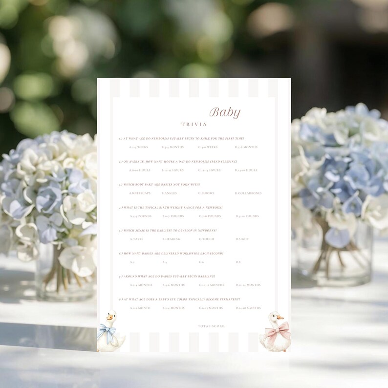 May include: A baby trivia game card with a striped background and the word "Baby" at the top. The card features trivia questions and answers. Two decorative duck illustrations are at the bottom. The card is surrounded by bouquets of blue and white flowers.