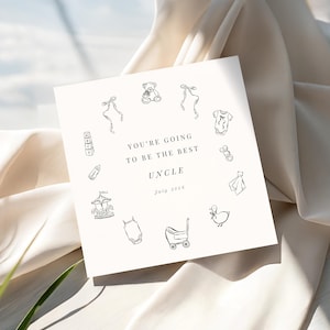 May include: A square, off-white card with black line drawings of baby-related items encircling the text "YOU'RE GOING TO BE THE BEST UNCLE July 2026". The illustrations include a teddy bear, baby clothes, and a carousel.