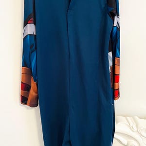May include: A dark blue Captain America costume. The long-sleeved jumpsuit features printed details on the sleeves and shoulders, including the iconic shield emblem. The back has a button closure at the neck. This costume is suitable for cosplay or themed events.