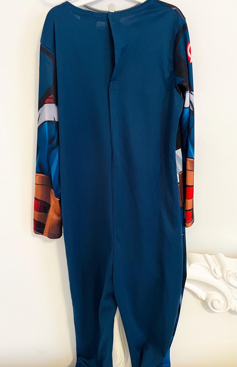 May include: A dark blue Captain America costume. The long-sleeved jumpsuit features printed details on the sleeves and shoulders, including the iconic shield emblem. The back has a button closure at the neck. This costume is suitable for cosplay or themed events.