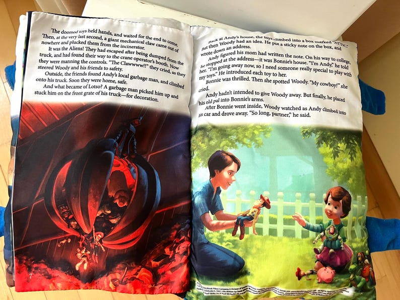 May include: An open storybook featuring two pages of text and illustrations. The left page shows a dark scene with a mechanical claw over a pile of toys. The right page depicts a person handing a cowboy doll to a child in a green outdoor setting.