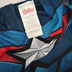 May include: Blue and red Avengers costume with a white star design. The costume has a tag with the Avengers logo and text. The costume is made of a lightweight material.
