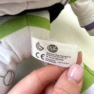 May include: A plush Buzz Lightyear toy, featuring white, green, and black accents. The toy has a label with text including "Whitehouse Leisure International Ltd" and "Disney/Pixar". The toy's design is based on the character from the Toy Story franchise.