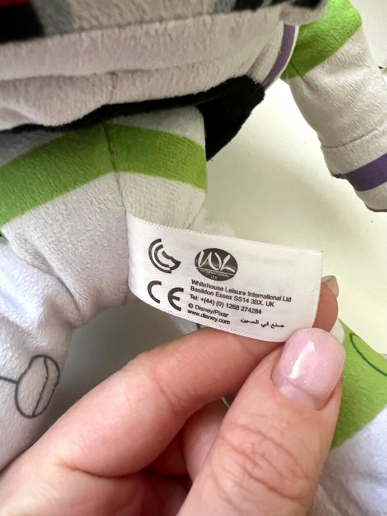 May include: A plush Buzz Lightyear toy, featuring white, green, and black accents. The toy has a label with text including "Whitehouse Leisure International Ltd" and "Disney/Pixar". The toy's design is based on the character from the Toy Story franchise.
