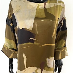 May include: A long-sleeved blouse with a round neckline and rolled-up cuffs. The top features an abstract pattern in shades of olive green, black, beige, and brown. The fabric appears to be a lightweight material, suitable for warmer weather.