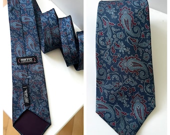 Könnte beinhalten: Eine blaue Seidenkrawatte mit einem Paisley-Muster in Rot- und Blautönen. Die Krawatte hat ein dunkelblaues Futter und ein Etikett mit der Aufschrift "Surrey Sophisticates" und "100% Seide".