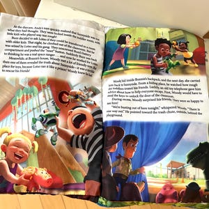 May include: A soft fabric book featuring Toy Story characters with printed text on two open pages. The left page shows a child playing with a pink piggy bank toy while Buzz Lightyear is in the background. The right page shows Woody and Rex.