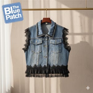 May include: A light blue denim vest with black lace trim and accents. The vest features a collared neckline with small black embellishments and two front pockets. The Blue Patch logo is visible in the upper left corner.