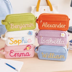 Può includere: Sei astucci in velluto a coste in vari colori, ciascuno ricamato con un nome: Benjamin, Alexander, Sophia, Isabella, Emma e William. Gli astucci rettangolari hanno una chiusura a zip e una piccola maniglia laterale. Sono inclusi decori floreali e di caramelle.