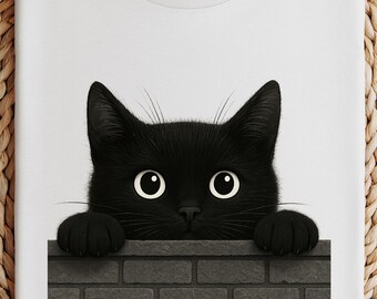 May include: White t-shirt featuring a black cat graphic. The cat's head and paws are visible, peeking over a gray brick wall. The cat has large, round eyes and a curious expression. The shirt is folded on a woven, circular surface.