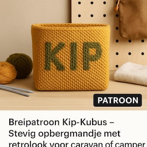 May include: A mustard yellow, knitted storage basket with the word "KIP" in green letters. The basket is rectangular and sits on a wooden surface. Knitting needles and yarn balls are visible.