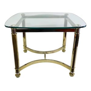 May include: A brass and glass coffee table with a square glass top and a curved brass base.