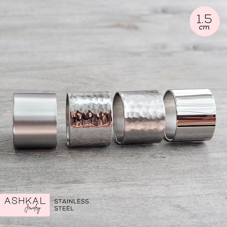 May include: Four stainless steel rings, each with a different finish. The rings are 1.5 inches in diameter and have a hammered, polished, and brushed finish. The rings are arranged in a row on a light gray surface. The text "ASHKAL Jewelry" and "STAINLESS STEEL" is visible at the bottom of the image.
