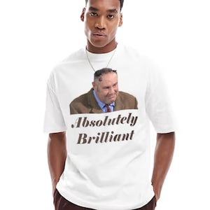 Pode incluir: T-shirt branca com um gráfico de um homem de blazer castanho e camisa azul, com as palavras "Absolutely Brilliant" em texto castanho. A t-shirt é usada por uma pessoa.