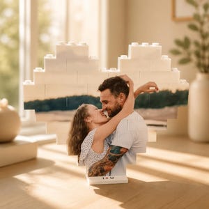 Peut inclure: Un cadre photo en forme de cœur composé de briques blanches. Le cadre affiche une photographie d'un couple s'embrassant. La base du cadre porte l'inscription "I ♥ U".