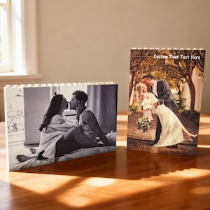 Puede incluir: Dos rompecabezas fotográficos personalizados. Uno es una imagen en blanco y negro de una pareja besándose. El otro es una imagen en color de una pareja besándose, con el texto "Custom Your Text Here" en la parte superior. Ambos rompecabezas están sobre una superficie de madera.