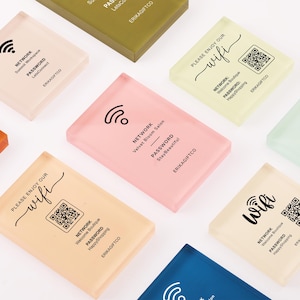May include: A collection of rectangular acrylic signs in various pastel colors, each featuring printed black text for Wi-Fi network names, passwords, and QR codes. The signs include the brand name ERIKAGIFTCO and icons for wireless internet connectivity.
