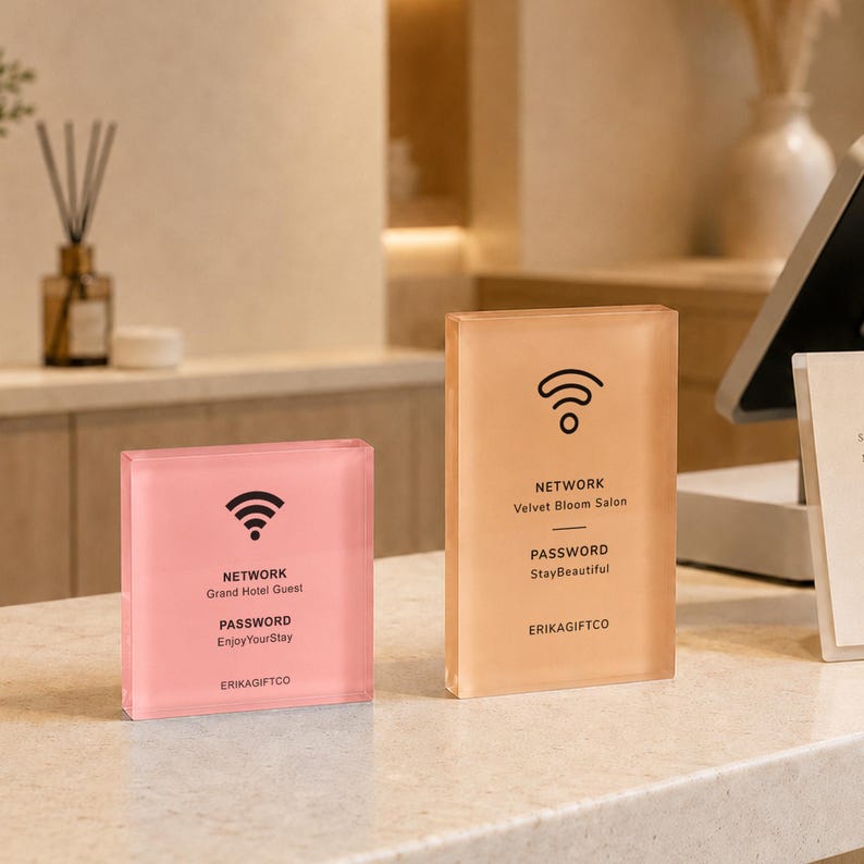 May include: Two rectangular acrylic signs with black text and Wi-Fi icons. The smaller pink sign displays NETWORK Grand Hotel Guest, PASSWORD EnjoyYourStay, and ERIKAGIFTCO. The taller peach sign displays NETWORK Velvet Bloom Salon, PASSWORD StayBeautiful, and ERIKAGIFTCO.