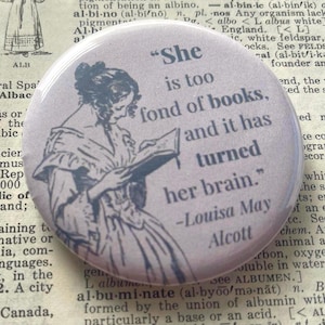 May include: A round, light brown button with a vintage illustration of a woman reading a book. The button features the quote, "She is too fond of books, and it has turned her brain." by Louisa May Alcott.