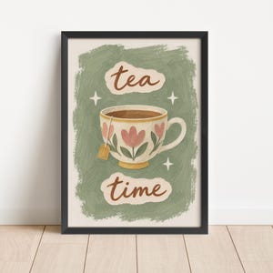 May include: A framed wall art print featuring a sage green textured background with a central illustration of a white teacup decorated with pink tulips. The cup contains dark tea and a tea bag. The text reads tea time with four white stars.