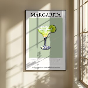 Op de afbeelding: Een ingelijste print met een margarita cocktail illustratie. De afbeelding toont een margarita in een glas met een zoutrand en een limoenpartje. Het woord "MARGARITA" staat bovenaan, met de ingredi&euml;nten en methode eronder.
