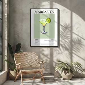 Op de afbeelding: Een ingelijste print met een Margarita cocktail illustratie. Het kunstwerk toont een groene cocktail in een glas met een steeltje met een limoen garnituur, tegen een lichtgroene achtergrond. Het woord "MARGARITA" staat bovenaan.