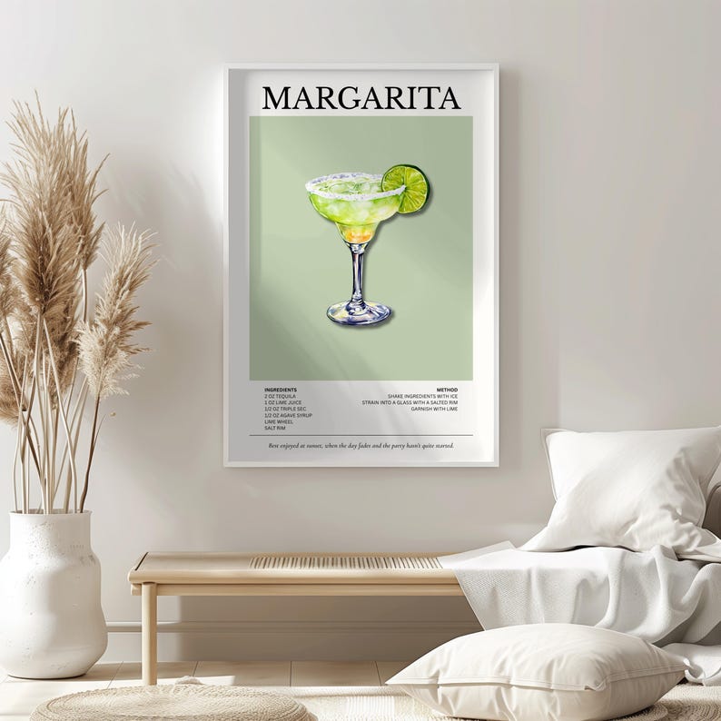 Op de afbeelding: Een ingelijste print met een margarita cocktail illustratie. Het kunstwerk toont een margarita in een glas met een steeltje met een limoenpartje, tegen een lichtgroene achtergrond. Het woord "MARGARITA" staat bovenaan.