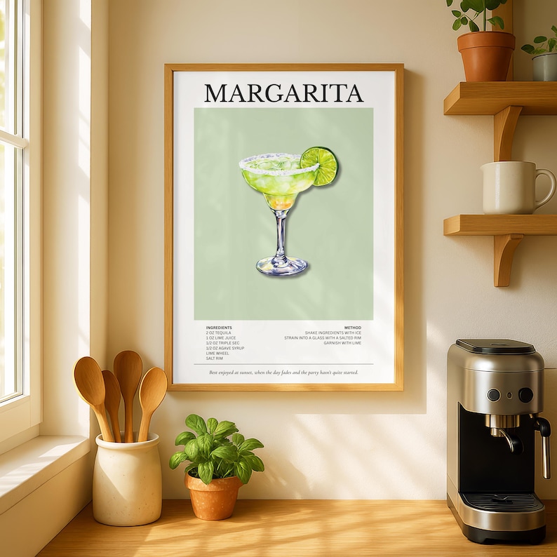 Op de afbeelding: Een ingelijste print met een margarita cocktail illustratie. Het kunstwerk toont een margarita in een glas met een limoenpartje, tegen een lichtgroene achtergrond. Het woord "MARGARITA" staat bovenaan.