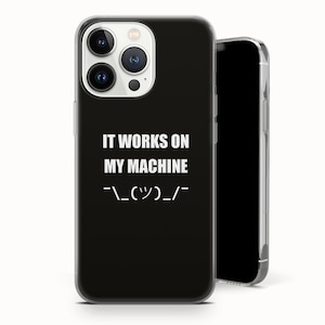 Op de afbeelding: Zwarte telefoonhoes met de witte tekst "IT WORKS ON MY MACHINE" en een emoticon. De telefoonhoes wordt op een witte achtergrond getoond. De telefoonhoes heeft een transparante rand.