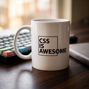 May include: A white ceramic mug featuring a black square outline and the black text CSS IS AWESOME printed on the front. The mug has a curved handle on the left side and a smooth, cylindrical body, standing upright with a clean, minimalist design.