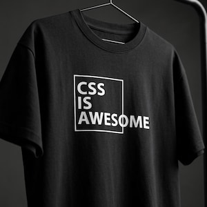 May include: A black short-sleeved t-shirt featuring a white square graphic on the chest. Inside the square, the text reads CSS IS AWESOME in a bold, sans-serif font. The garment is displayed on a black hanger against a dark grey background.