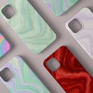 Peut inclure: Plusieurs coques de smartphone avec un motif marbré. Les coques présentent diverses couleurs, notamment vert, rouge, violet et un motif arc-en-ciel. Chaque coque a une découpe pour l'appareil photo et des coins arrondis.