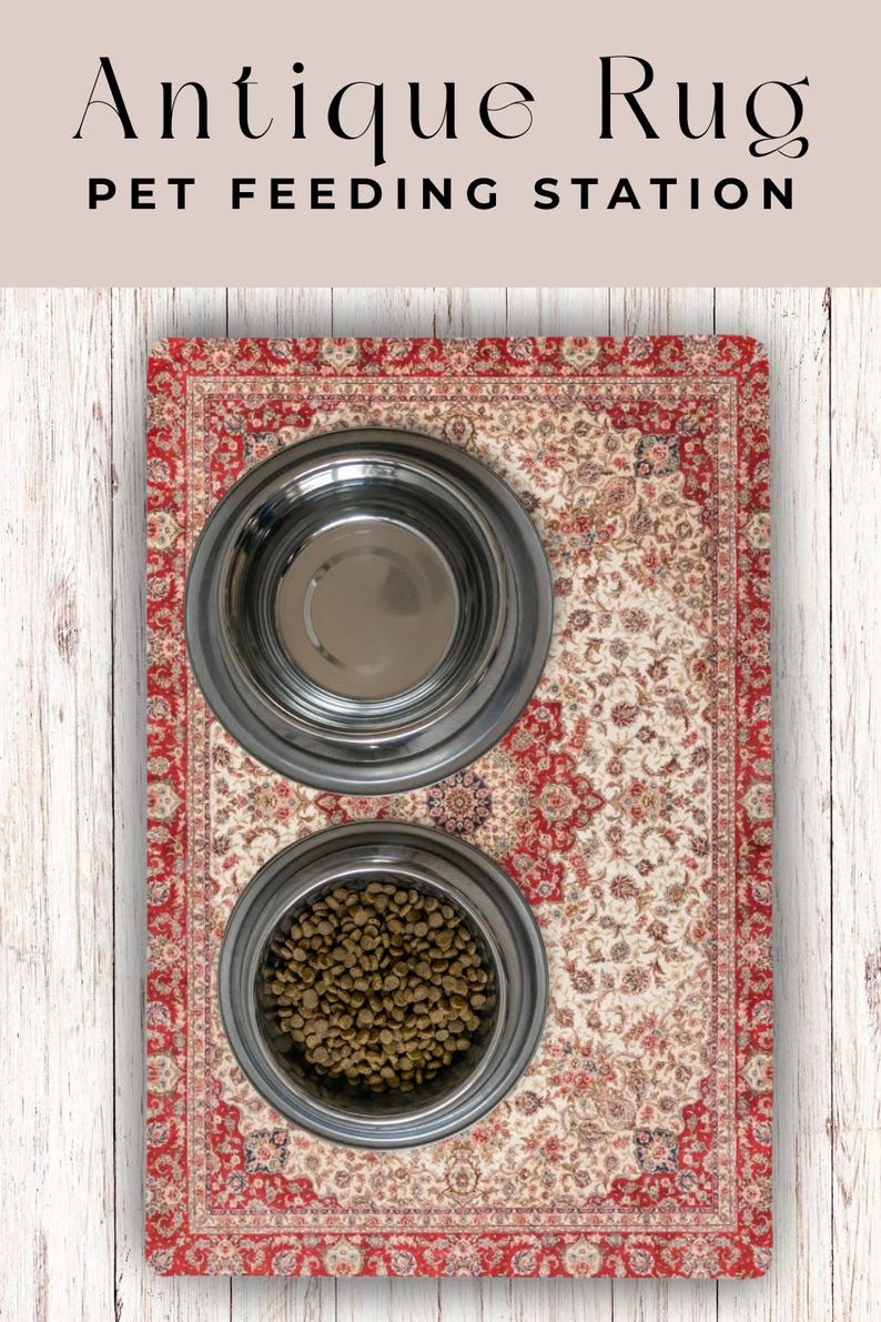 May include: An antique rug pet feeding station with two stainless steel bowls. One bowl is empty, and the other is filled with pet food. The rug has a red border and a cream-colored center with floral patterns. The text "Antique Rug PET FEEDING STATION" is at the top.