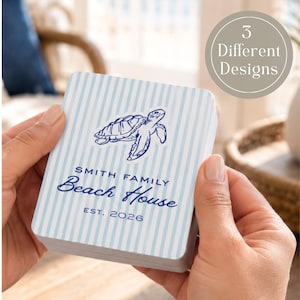 May include: A stack of light blue and white striped cards featuring a navy blue turtle illustration and the text "SMITH FAMILY Beach House EST. 2026". A circular graphic in the background says "3 Different Designs".