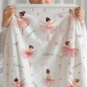 Girl holding a Dance Blanket for Girls that is Personalized with a name. The blanket features ballerinas dressed in pink tutus, bows, flowers, and butterflies.