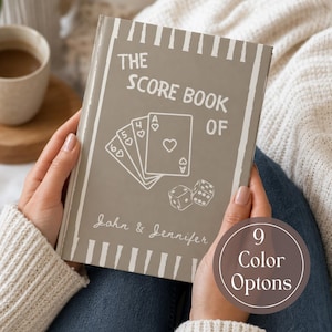 Puede incluir: Un libro de puntuaciones color topo con ilustraciones de líneas blancas que muestran una mano de cartas, dos dados y el texto THE SCORE BOOK OF John & Jennifer. La portada tiene un borde de rayas verticales y un sello 9 Color Options.