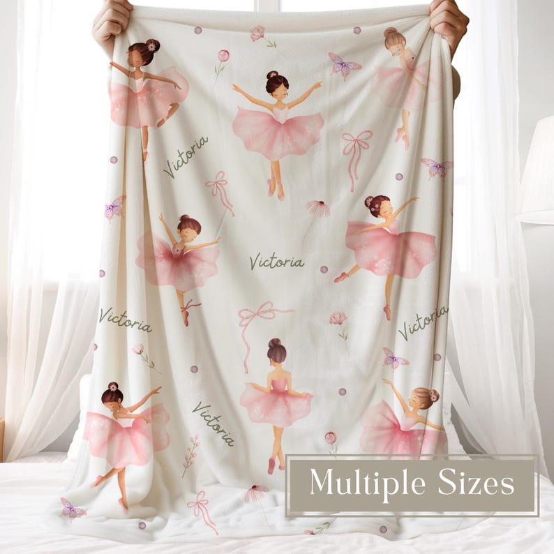 A woman is holding a Custom Ballerina Name Blanket for Girls featuring pink ballerinas, flowers, and butterflies. The blanket is customized with a name in script font.