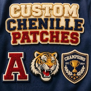Op de afbeelding: Close-up van op maat gemaakte chenille patches in crème, marineblauw en rood. De patches bevatten de tekst "CUSTOM CHENILLE PATCHES", een rode letter "A", een tijgerkop en een schild met een trofee en het woord "CHAMPIONS".
