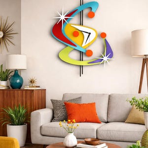May include: A vibrant, mid-century modern wall clock with an abstract design. The clock has a yellow, red, blue, and green colour scheme with orange and white accents. The clock hands are black.