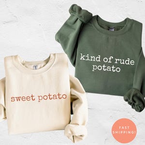 Może przedstawiać: Dwie bluzy z okrągłym dekoltem. Jedna jest kremowa z napisem "sweet potato" w brązowym tekście. Druga jest oliwkowozielona z napisem "kind of rude potato" w białym tekście. Bluzy mają długie rękawy i okrągłą pomarańczową naklejkę z napisem "FAST SHIPPING!"