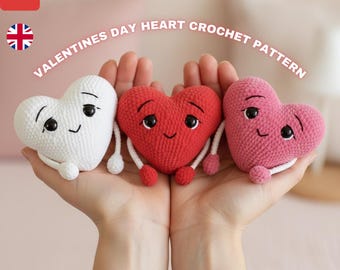 May include: Three crocheted heart-shaped plush toys in white, red, and pink, each with black eyes and a smiling face. The hearts have small arms and legs. The text "VALENTINES DAY HEART CROCHET PATTERN" is in the background.