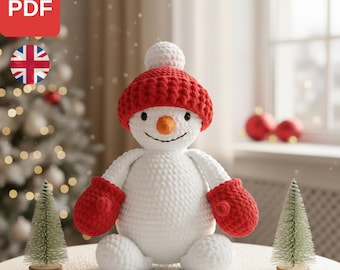 May include: A handmade crochet snowman wearing a red hat and mittens, with a carrot nose. The snowman is on a table, with two small Christmas trees. The text "SNOWMAN PATTERN" is displayed at the bottom of the image.