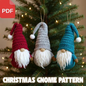 Pode incluir: Três enfeites de gnomos de crochê feitos à mão em vermelho, cinza e verde-azulado, cada um com barba branca, nariz pequeno bege e pompom branco no chapéu. Os enfeites estão pendurados em uma árvore de Natal. O texto "CHRISTMAS GNOME PATTERN" está na parte inferior.