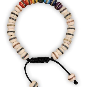 May include: A rainbow-colored bracelet with white beads and a black cord. The beads are decorated with intricate patterns.