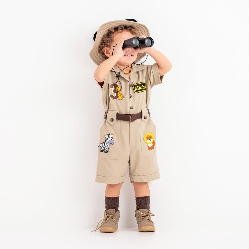 a little boy in a safari outfit looking through a pair of binoculars