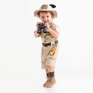 a little boy dressed in a safari outfit holding a camera