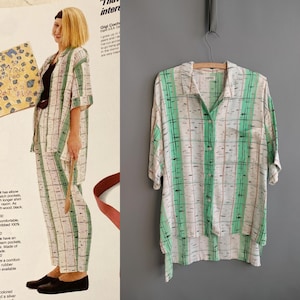Può includere: Una camicia vintage Esprit con motivo a quadri verdi e bianchi. La camicia a maniche corte ha una tasca sul petto ed è appesa a una gruccia di legno. La camicia fa parte di un completo coordinato, come si vede nell'immagine.
