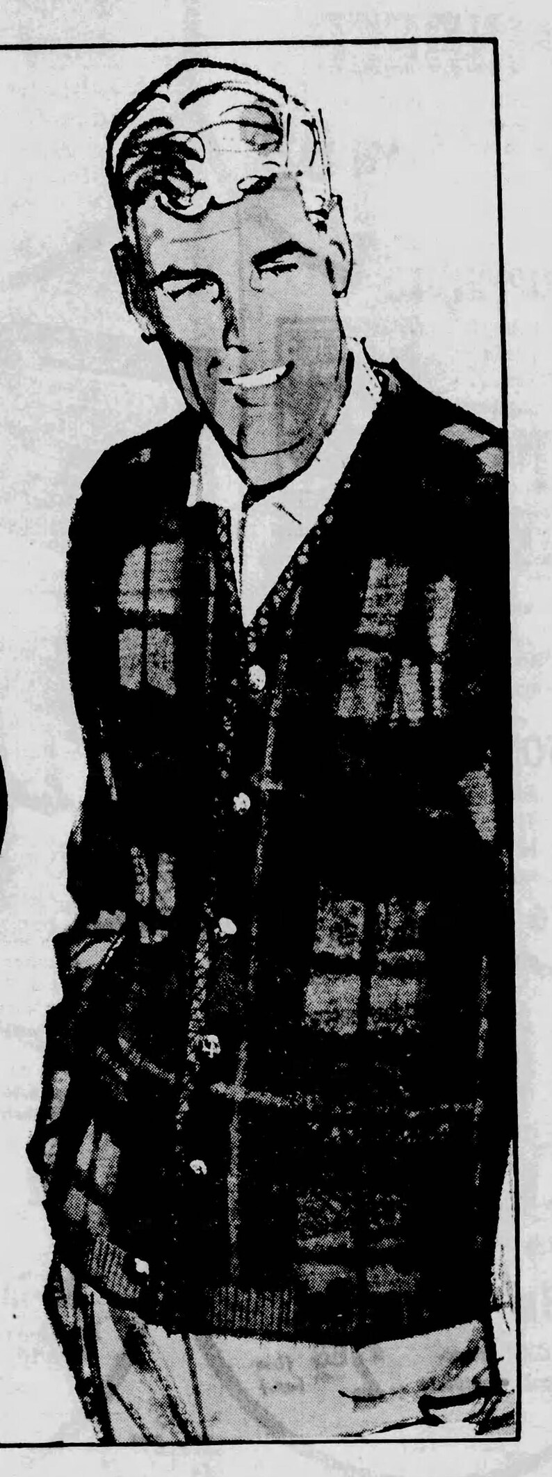 May include: A black and brown plaid cardigan sweater over a white collared shirt. The sweater has a button-up front and is worn by a person. The image is a vintage illustration.