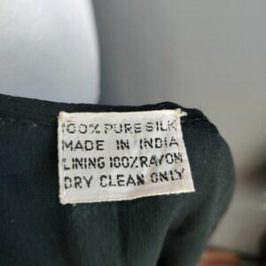 May include: A white tag with black text that reads "100% Pure Silk Made in India Lining 100% Rayon Dry Clean Only".